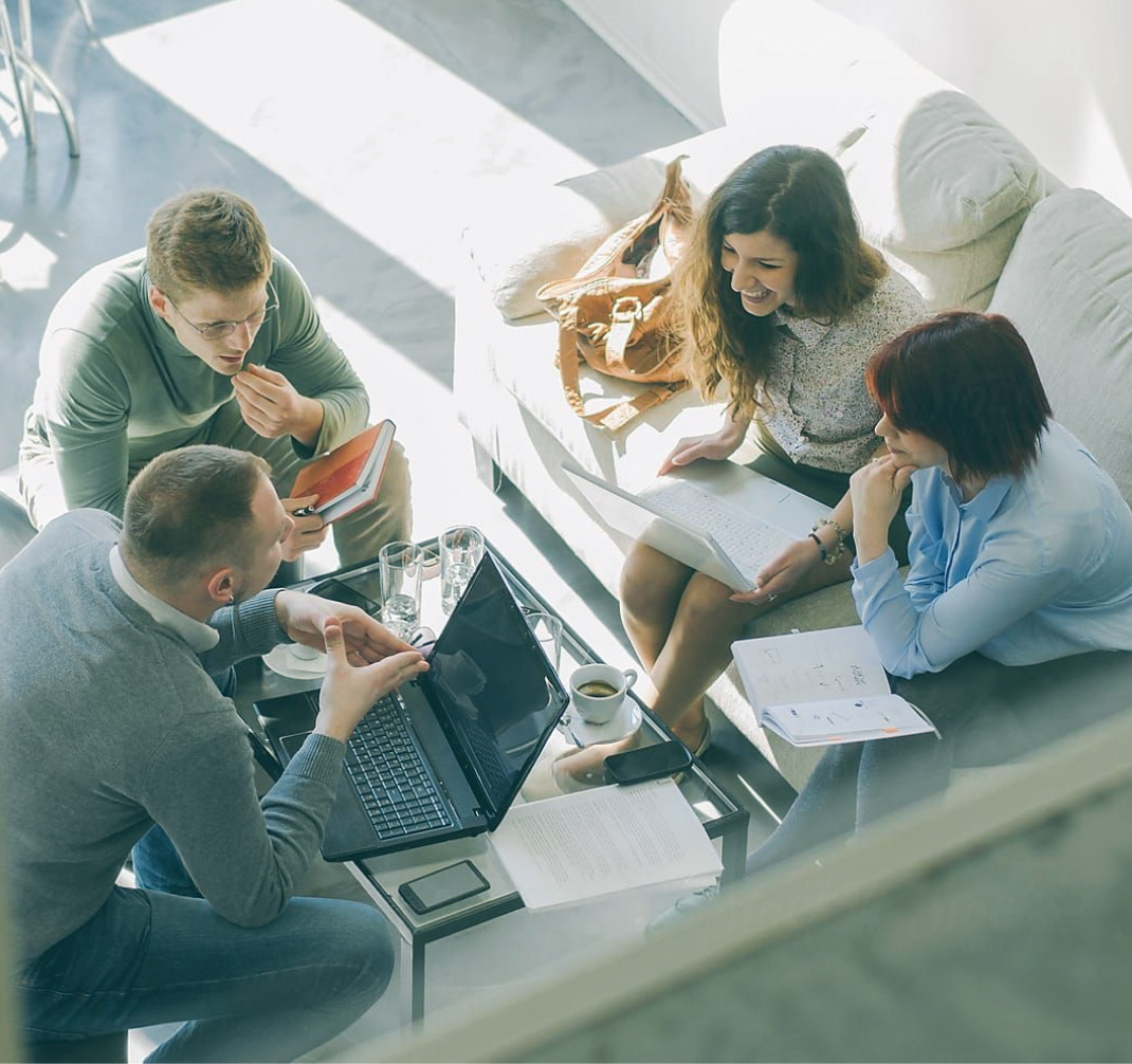 A team discussing work together around a laptop
